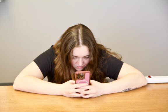 A graduate student slouches while she looks at her smartphone.